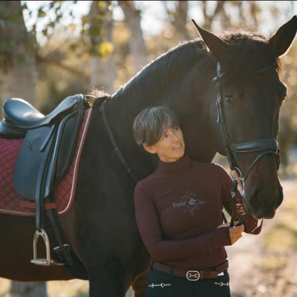 Claire van Gelder junto a su caballo ensillado en un día de otoño